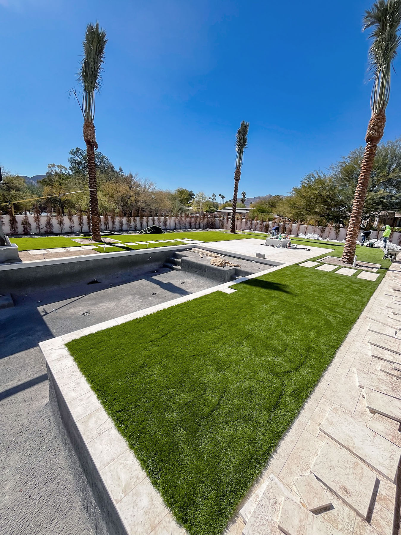 artificial-turf-and-travertine-poolside-installation poolside turf installation under construction in Scottsdale, AZ
